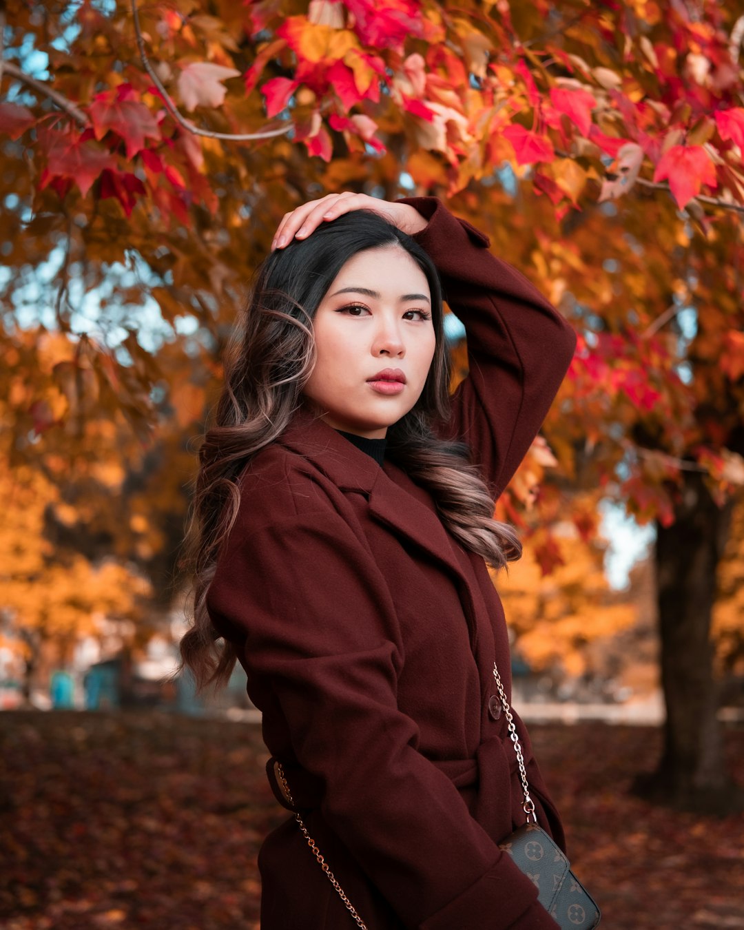woman in brown coat standing under brown leaves during daytime