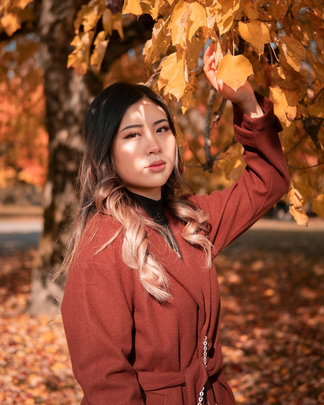 girl in pink jacket holding brown dried leaves