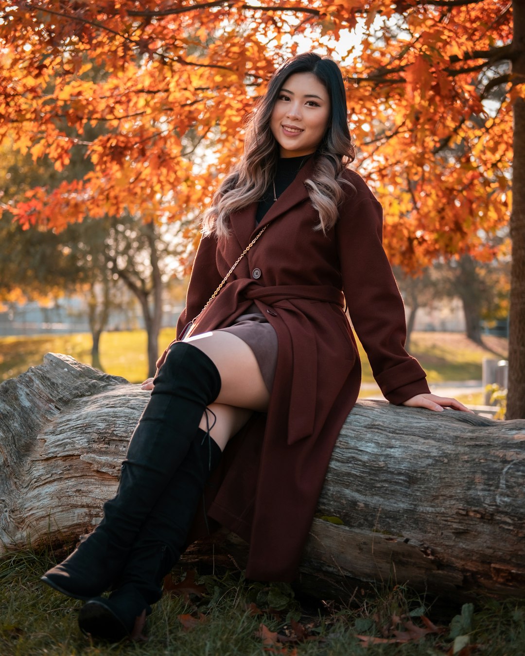 woman in brown coat sitting on brown log