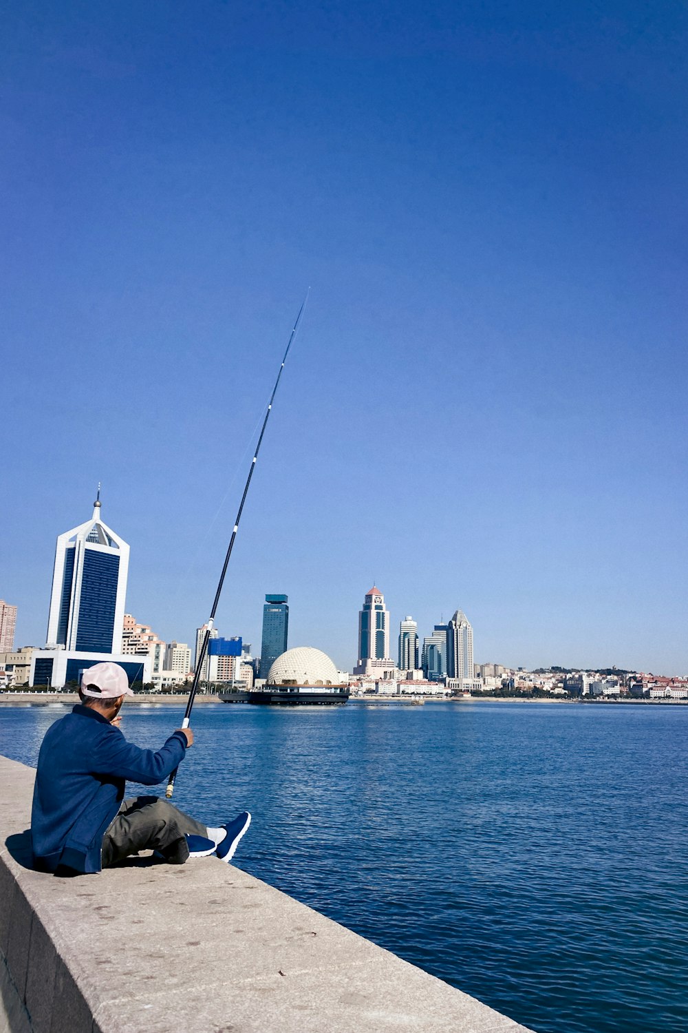 a man sitting on the edge of a pier fishing