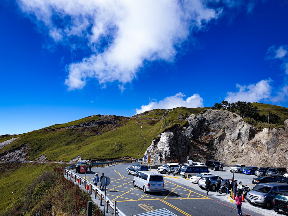 cars on road near mountain under blue sky during daytime