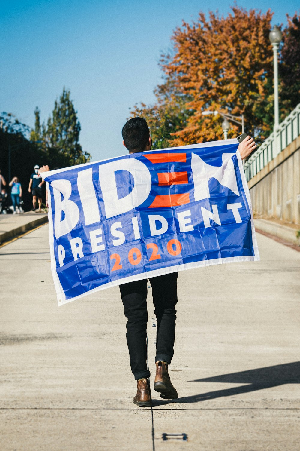 man in black jacket holding blue and white banner