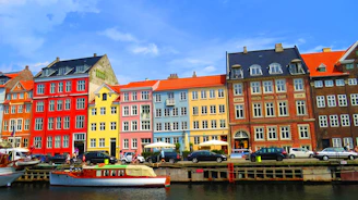 Colorful buildings line a canal with boats and cars.