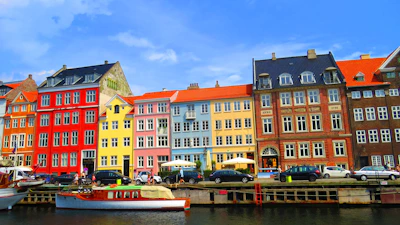 Colorful buildings line a canal with boats and cars.