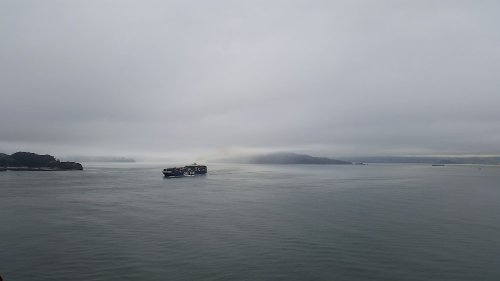 black boat on sea under white sky during daytime