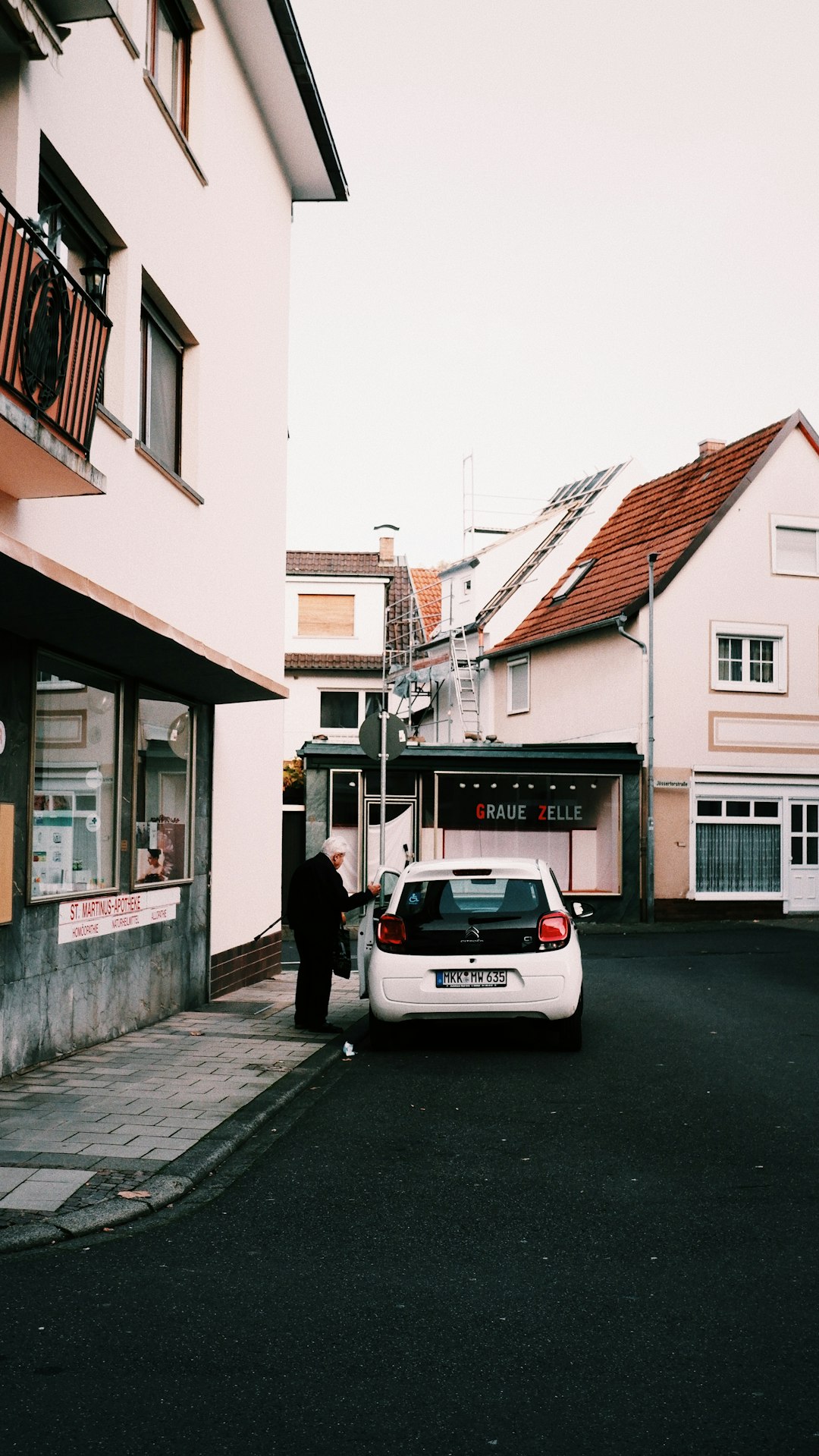 man in black jacket standing beside white car during daytime