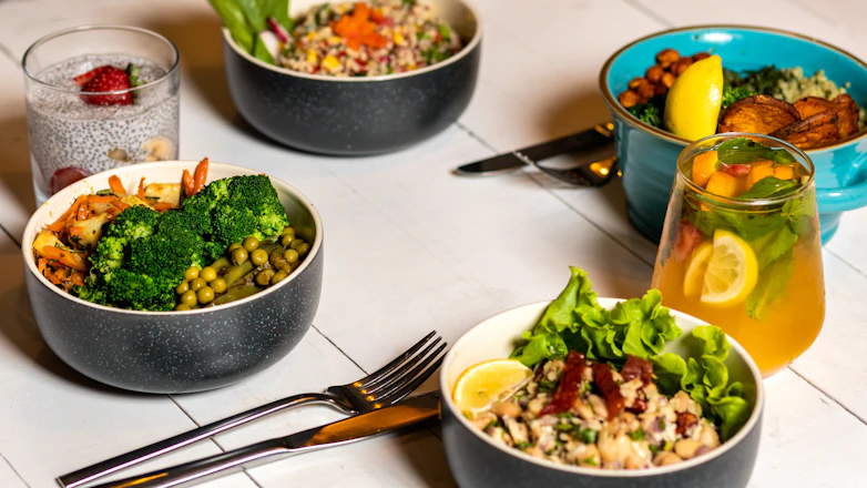 A colorful spread of healthy meals including oatmeal, salad, grilled chicken, and fresh juice on a rustic wooden table.