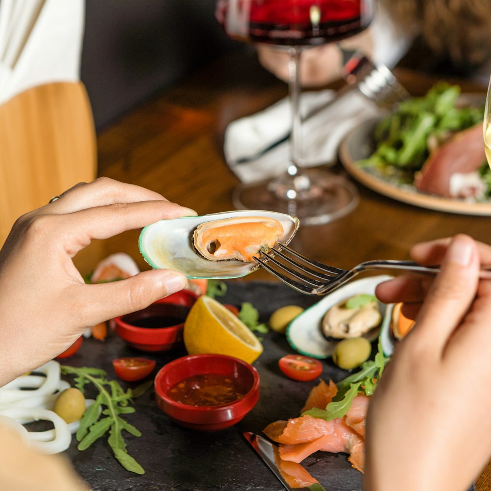 person holding stainless steel fork and knife slicing vegetable