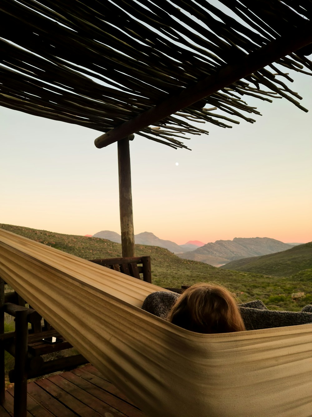 woman sitting on brown wooden bench looking at mountains during daytime