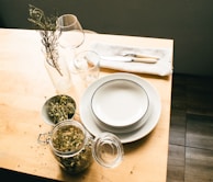 A dining table set with simple white plates, linen napkins, and a vase of fresh wildflowers.