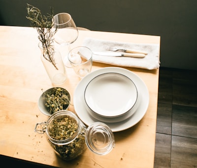 A rustic wooden table set with simple ceramic plates and dried flower arrangements.