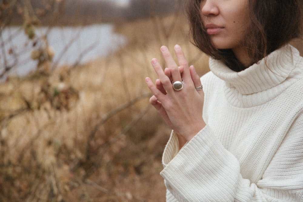 woman in white turtleneck sweater holding her hair