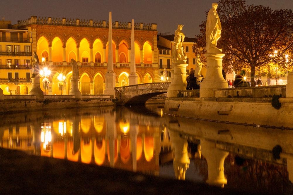 edificio in cemento bianco vicino allo specchio d'acqua durante la notte