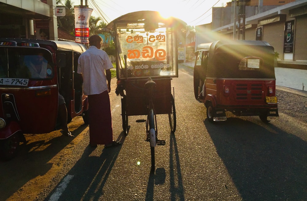 man in white shirt and black pants standing beside red bus