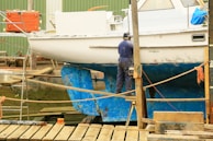 man in blue denim jacket standing on brown wooden dock during daytime