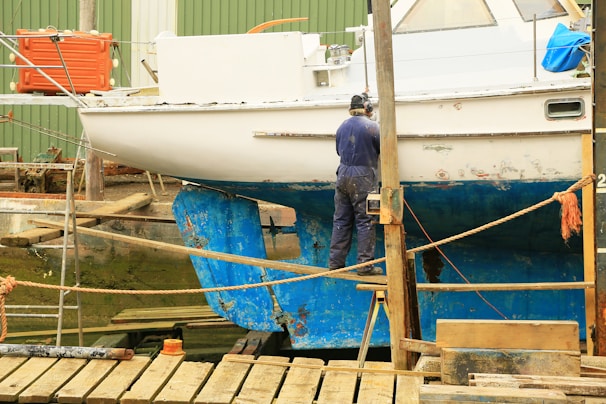man in blue denim jacket standing on brown wooden dock during daytime