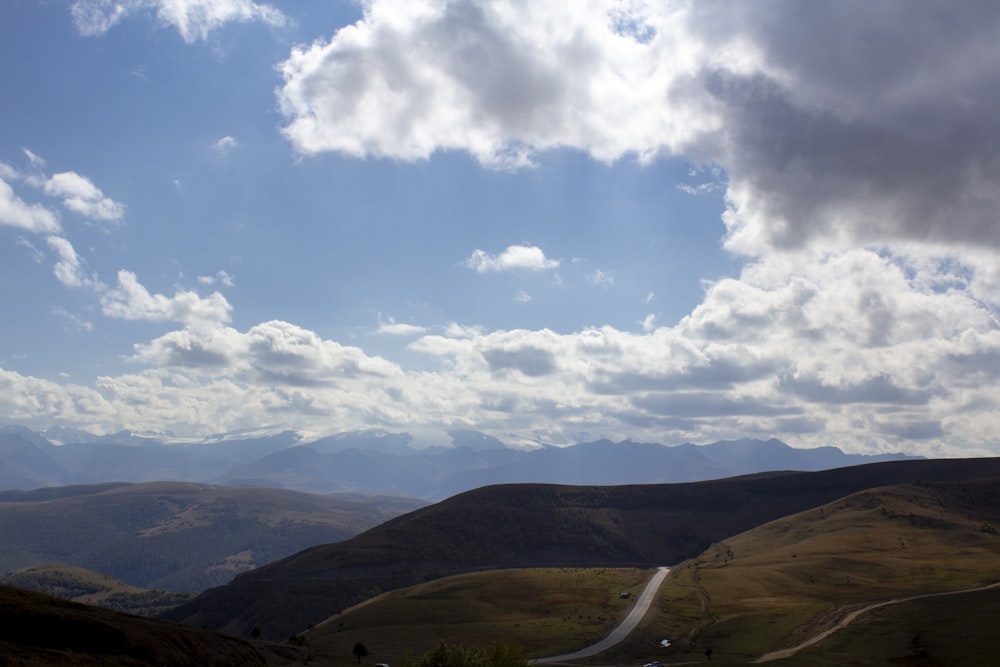 montañas verdes bajo nubes blancas y cielo azul durante el día