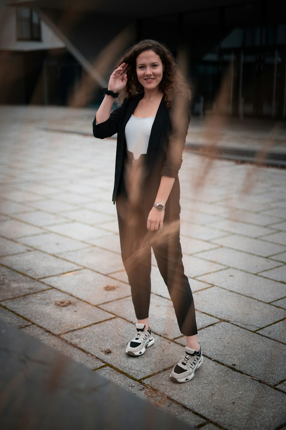 woman in black blazer and brown pants standing on sidewalk during daytime