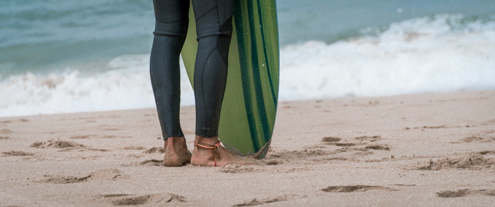 person in green and blue pants holding green and blue surfboard