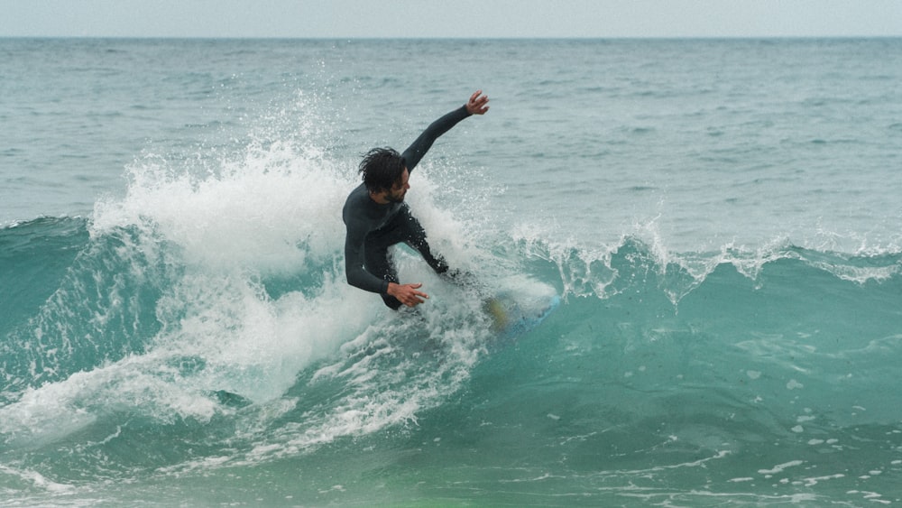 man in black shirt surfing on sea waves during daytime