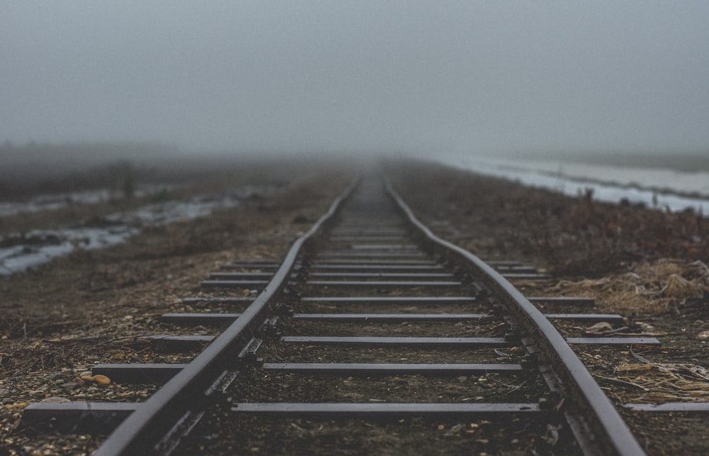 black metal train rail near body of water during daytime