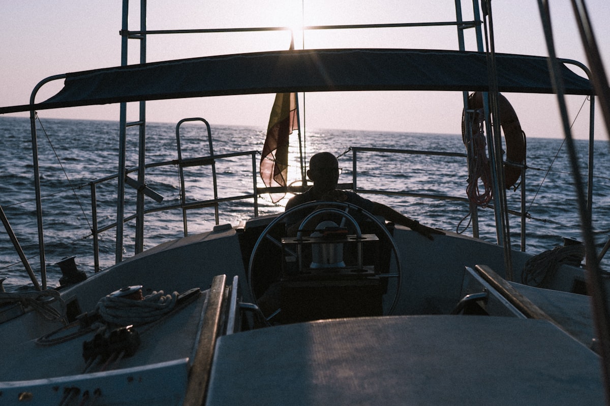 Patrón al timón de un velero al atardecer representando la certificación RYA Yachtmaster