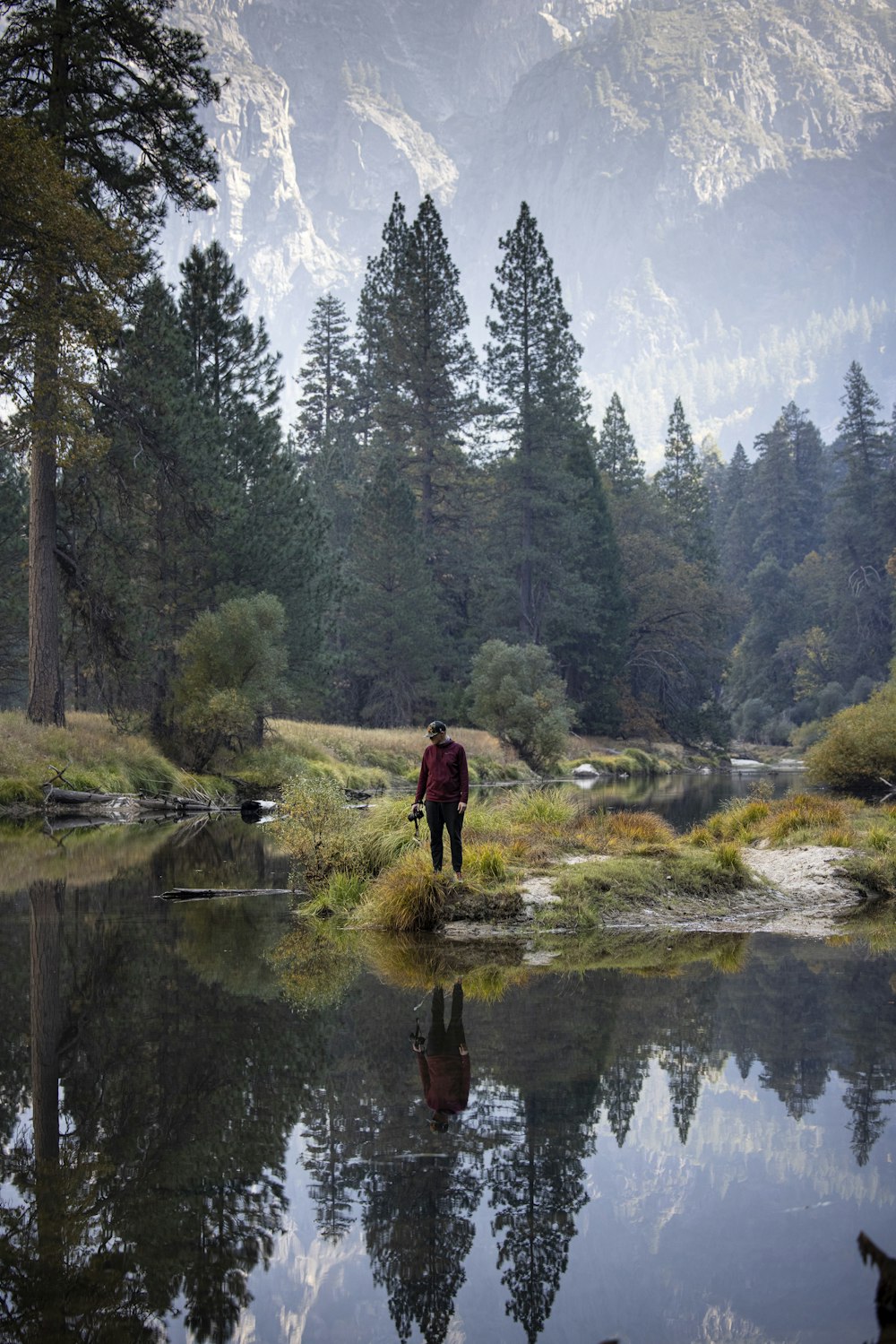 man in red jacket standing on river during daytime