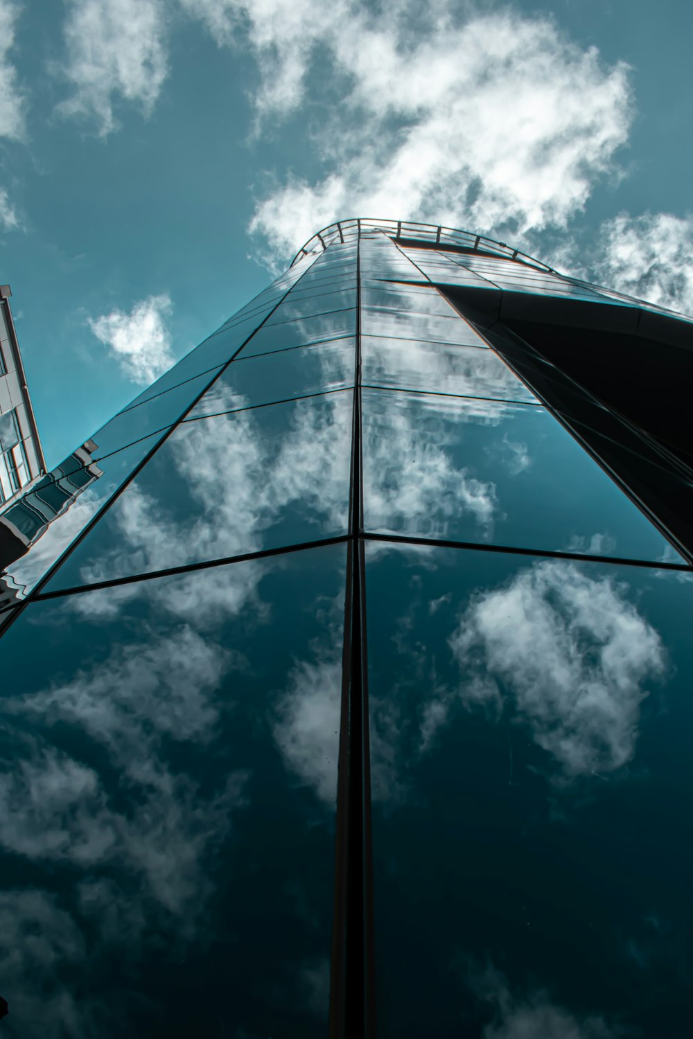 low angle photography of gray metal tower under blue sky and white clouds during daytime