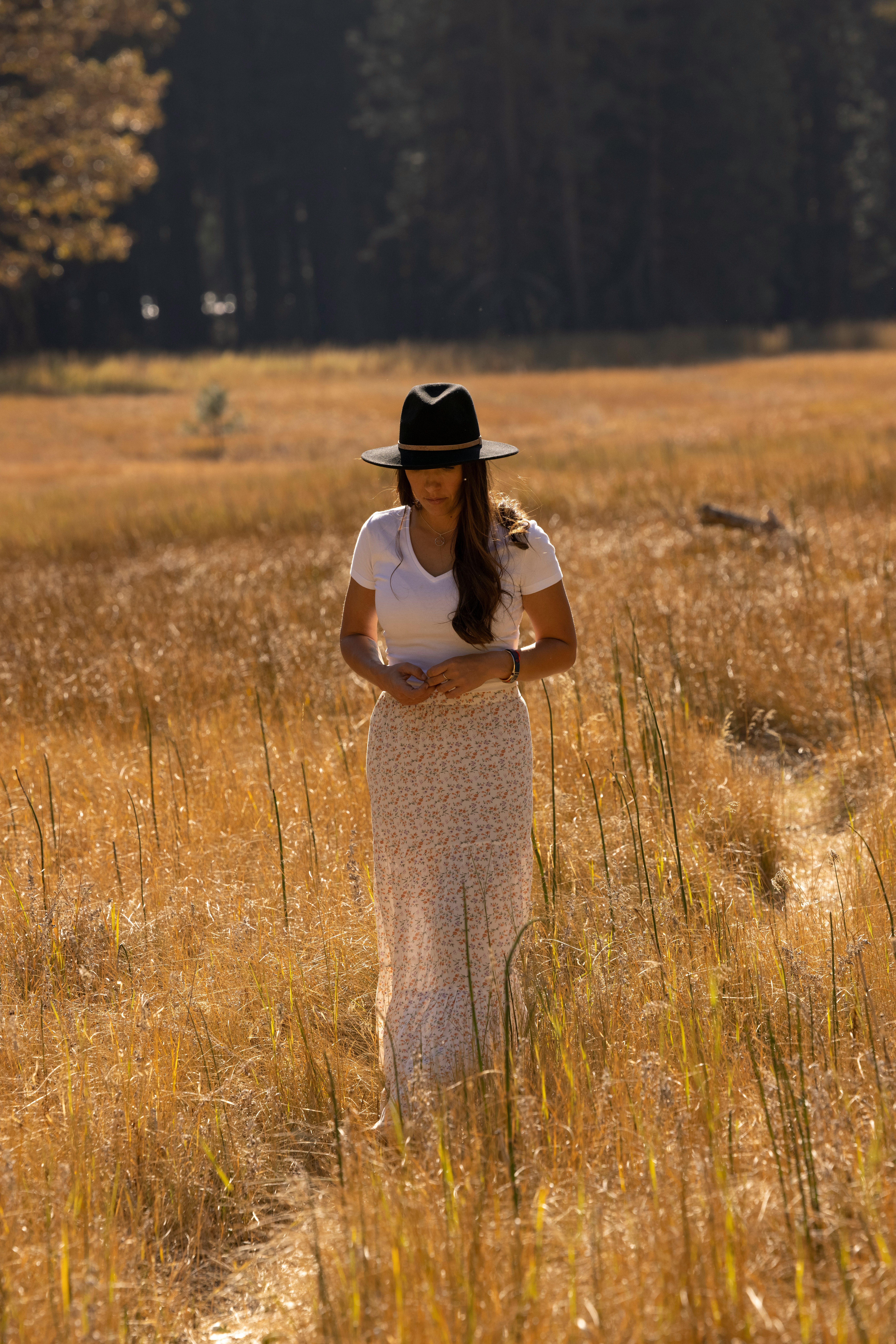 woman in white shirt and brown hat standing on brown grass field during daytime