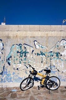 Modern bicycle leaning against a colorful urban wall on a sunny day