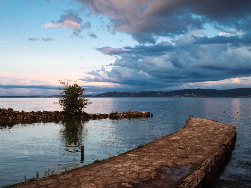 brown wooden dock on lake under blue sky and white clouds during daytime