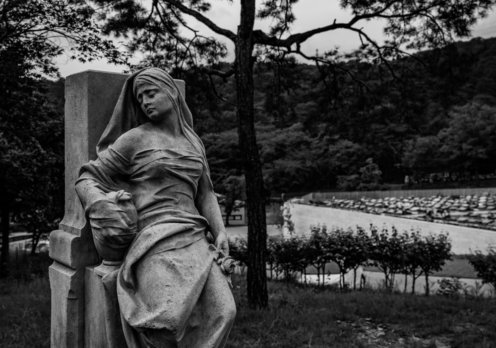 Photo en niveaux de gris d’une femme assise sur un champ d’herbe