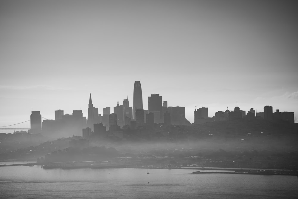 grayscale photo of city buildings near body of water