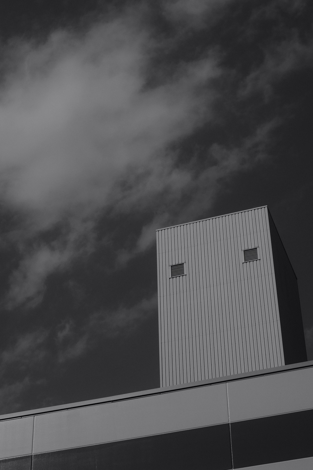 grayscale photo of building under cloudy sky