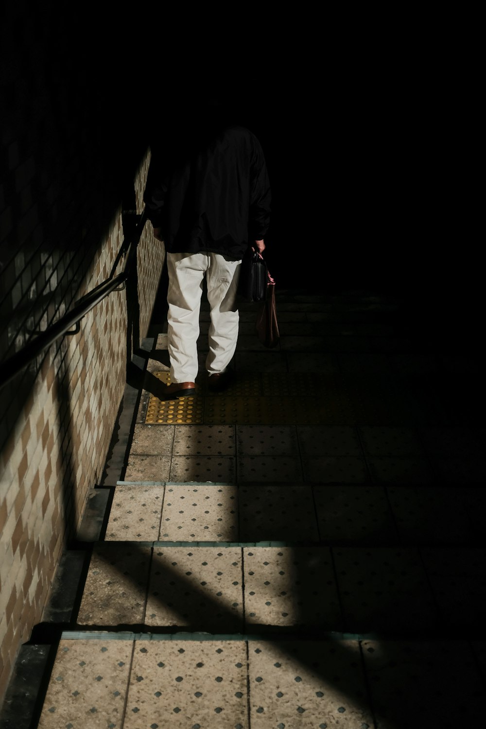 man in black jacket and white pants walking on hallway