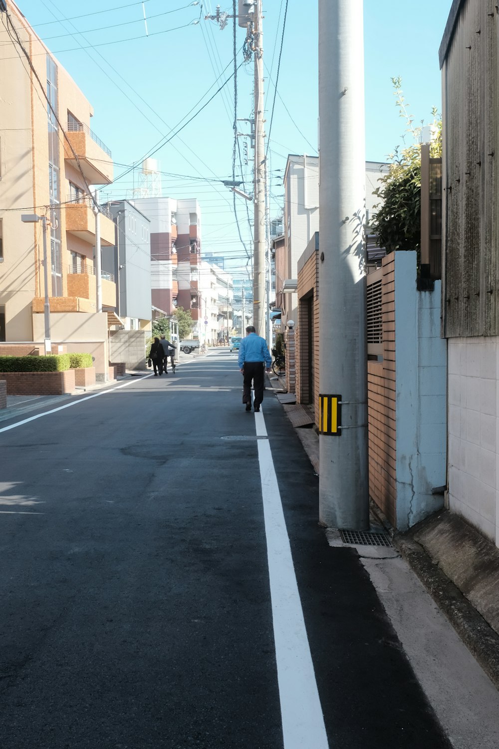 man in blue jacket and black pants walking on sidewalk during daytime