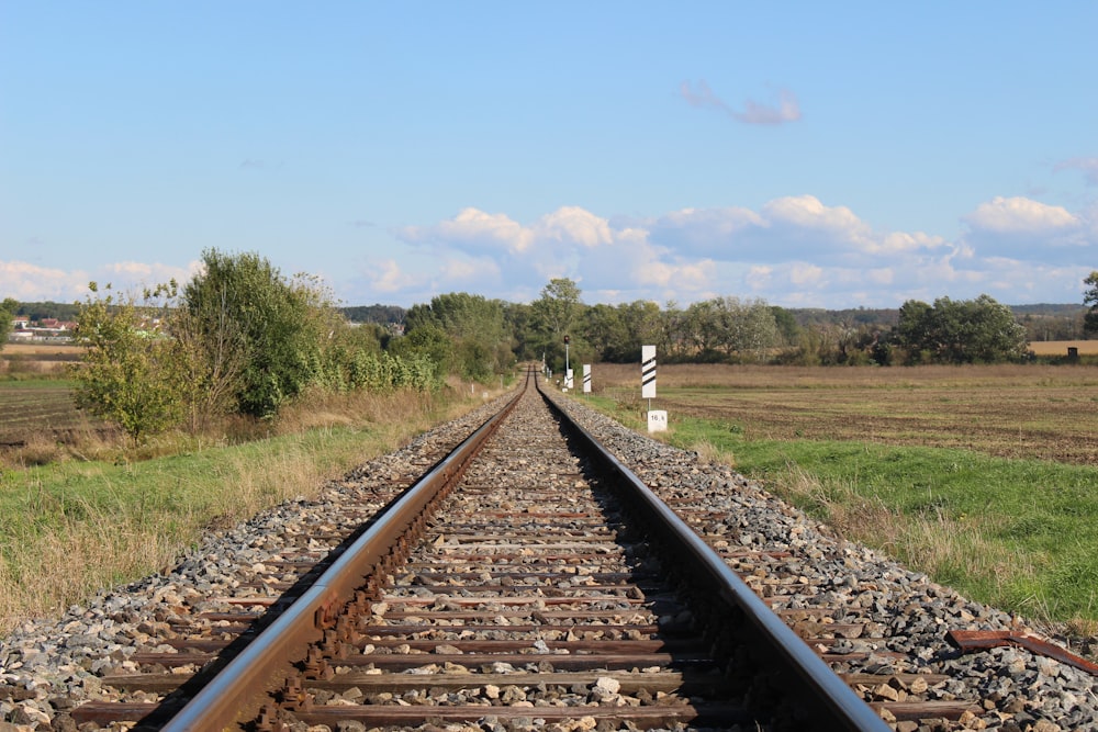 brown train rail under blue sky during daytime