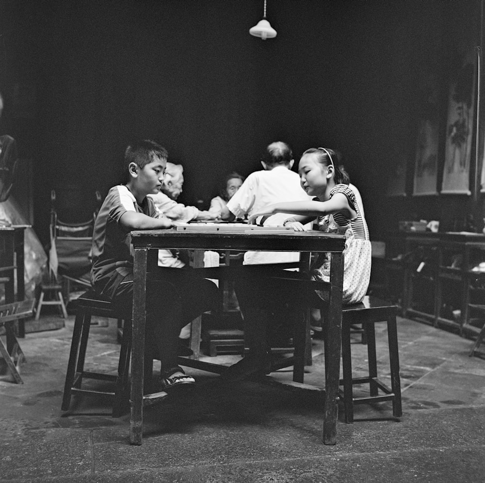 grayscale photo of 2 men sitting on chair