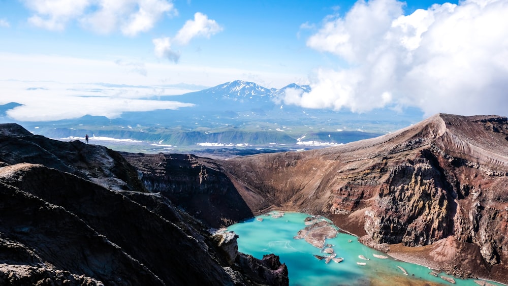 montagne marroni e grigie vicino allo specchio d'acqua sotto il cielo blu durante il giorno