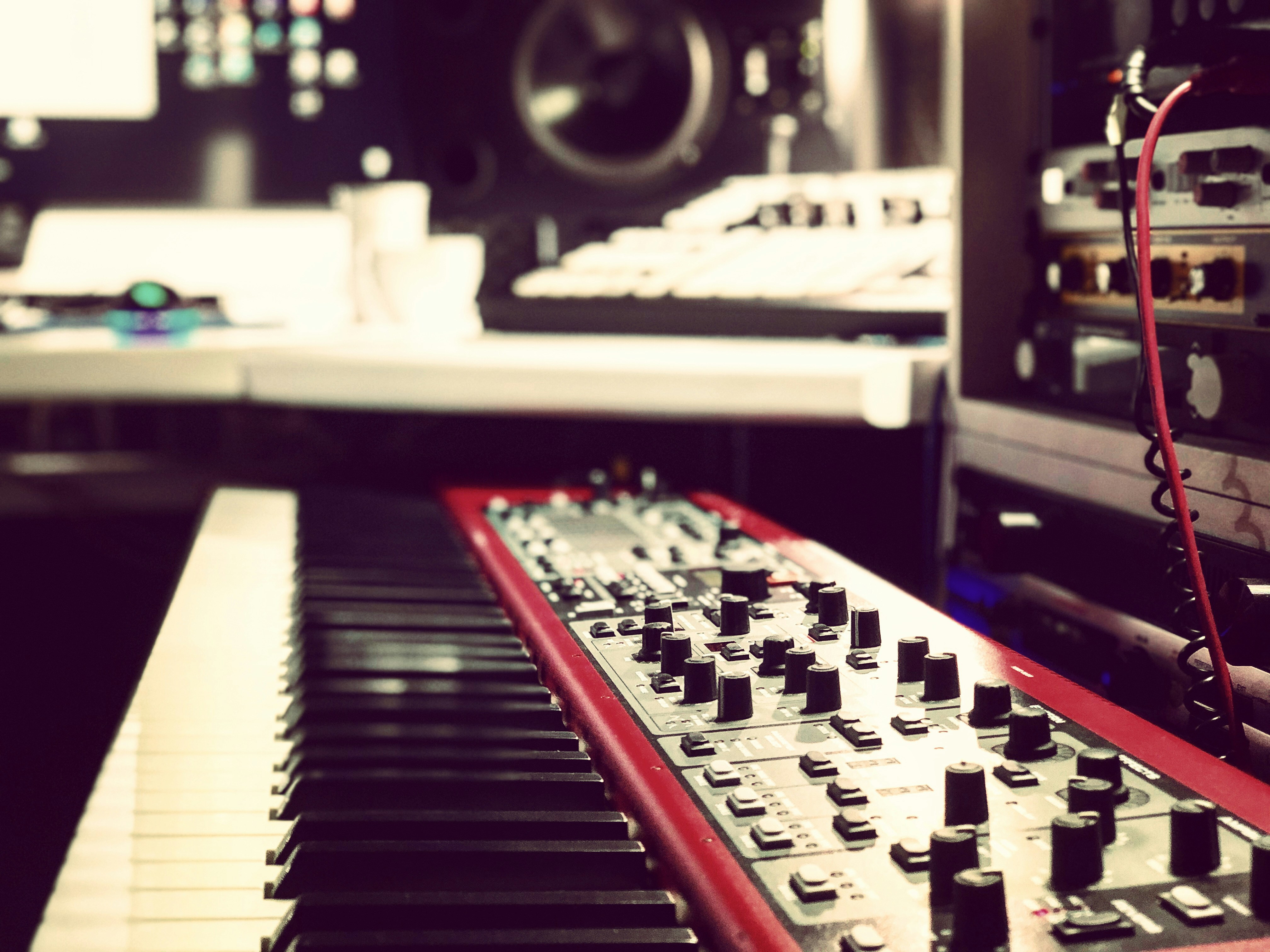 Dimly lit recording studio with analog synthesizers glowing in the dark