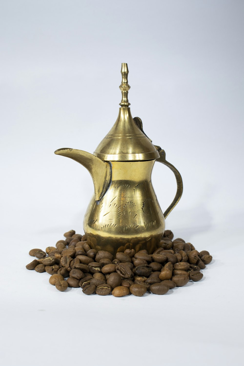 Gold- und Silberteekanne auf braunen Kaffeebohnen