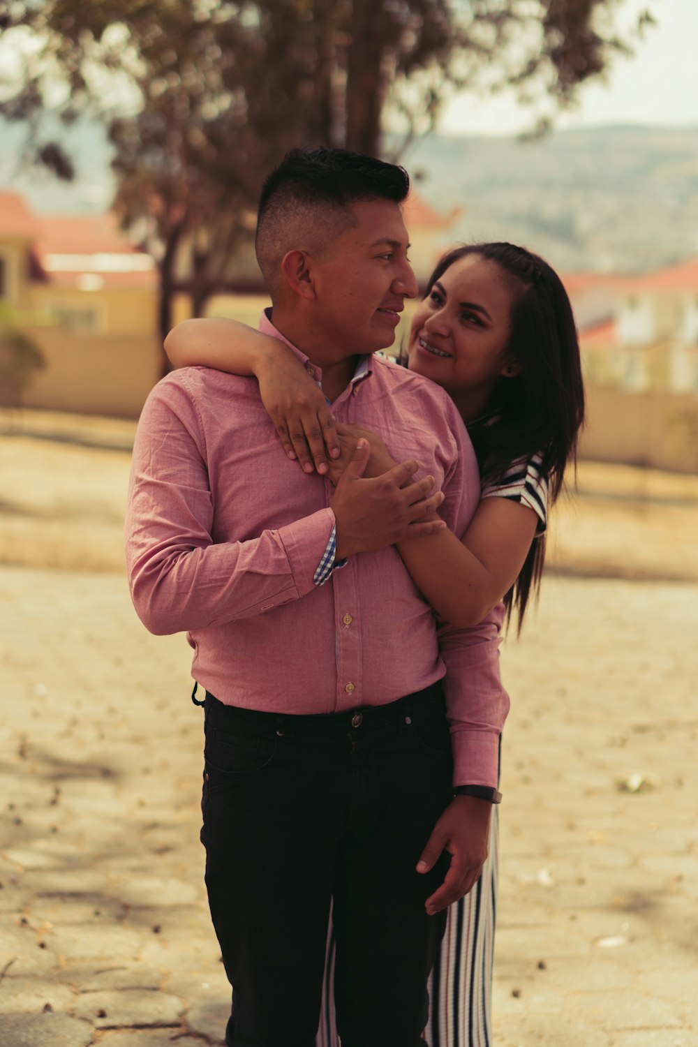 man in pink dress shirt carrying girl in pink long sleeve shirt