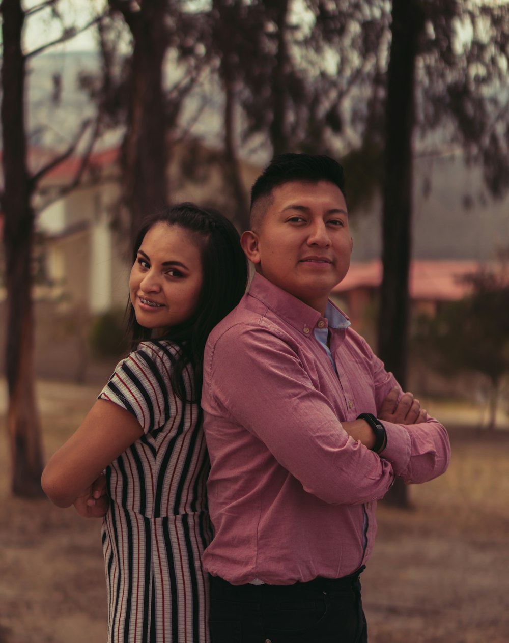 man in pink dress shirt beside woman in black and white stripe shirt