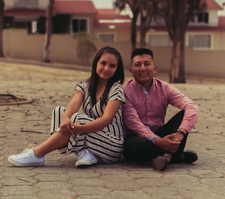 man and woman sitting on brown sand during daytime