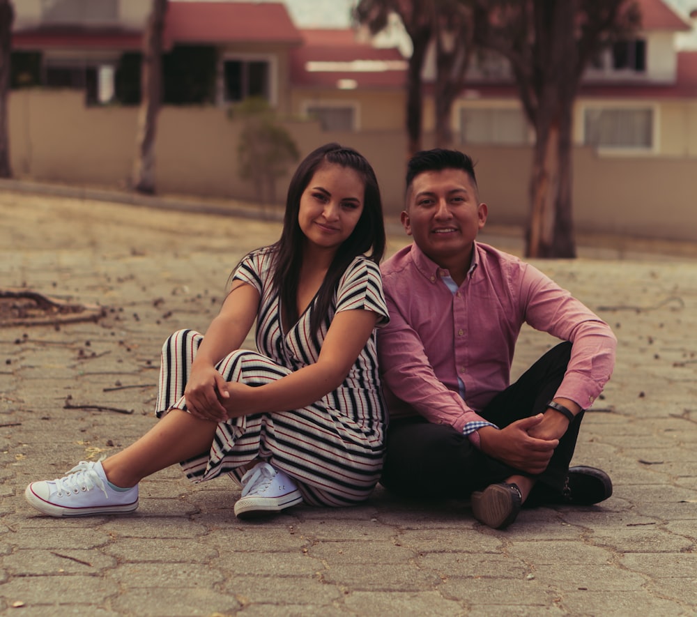 man and woman sitting on brown sand during daytime