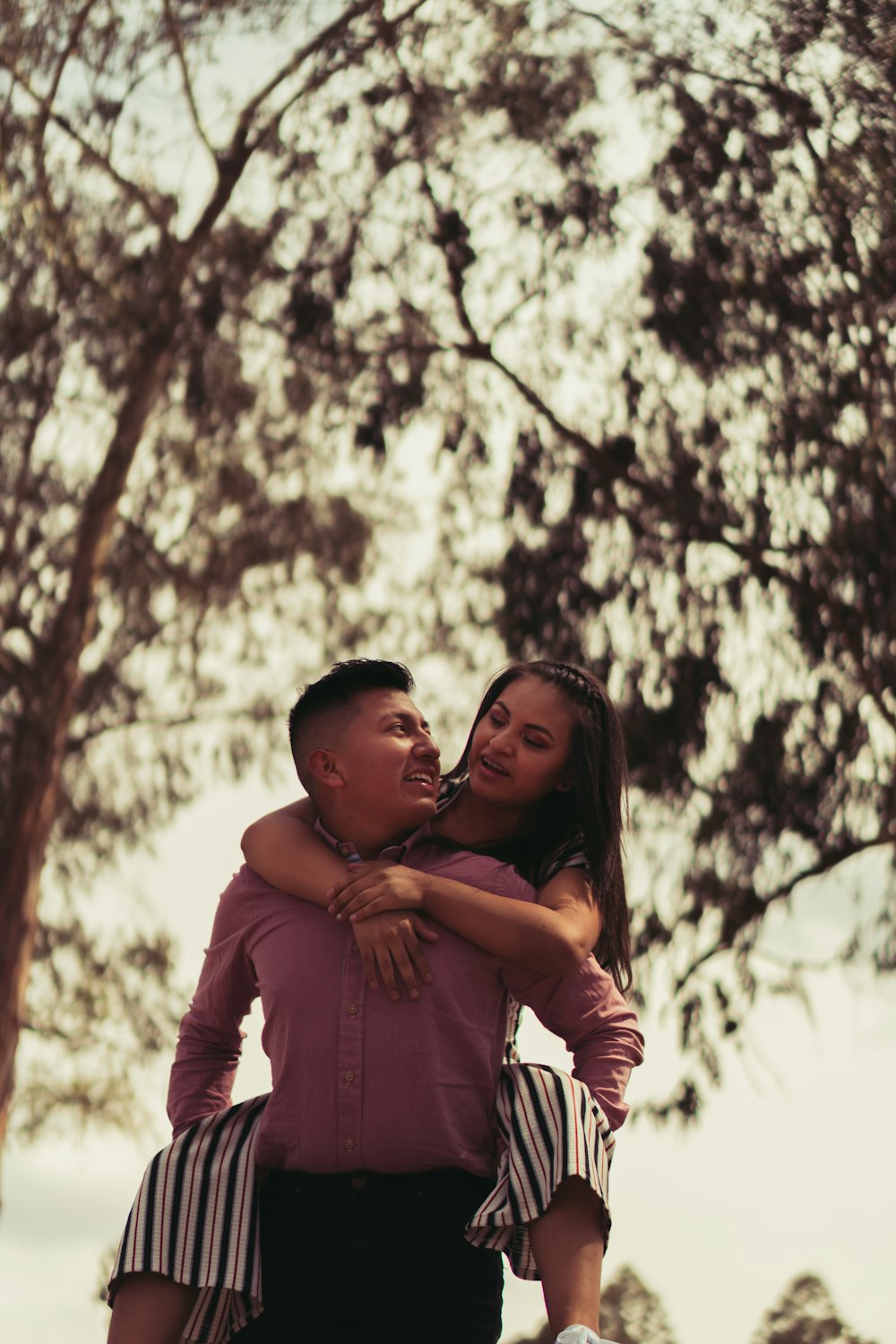 man in red dress shirt hugging woman in black dress