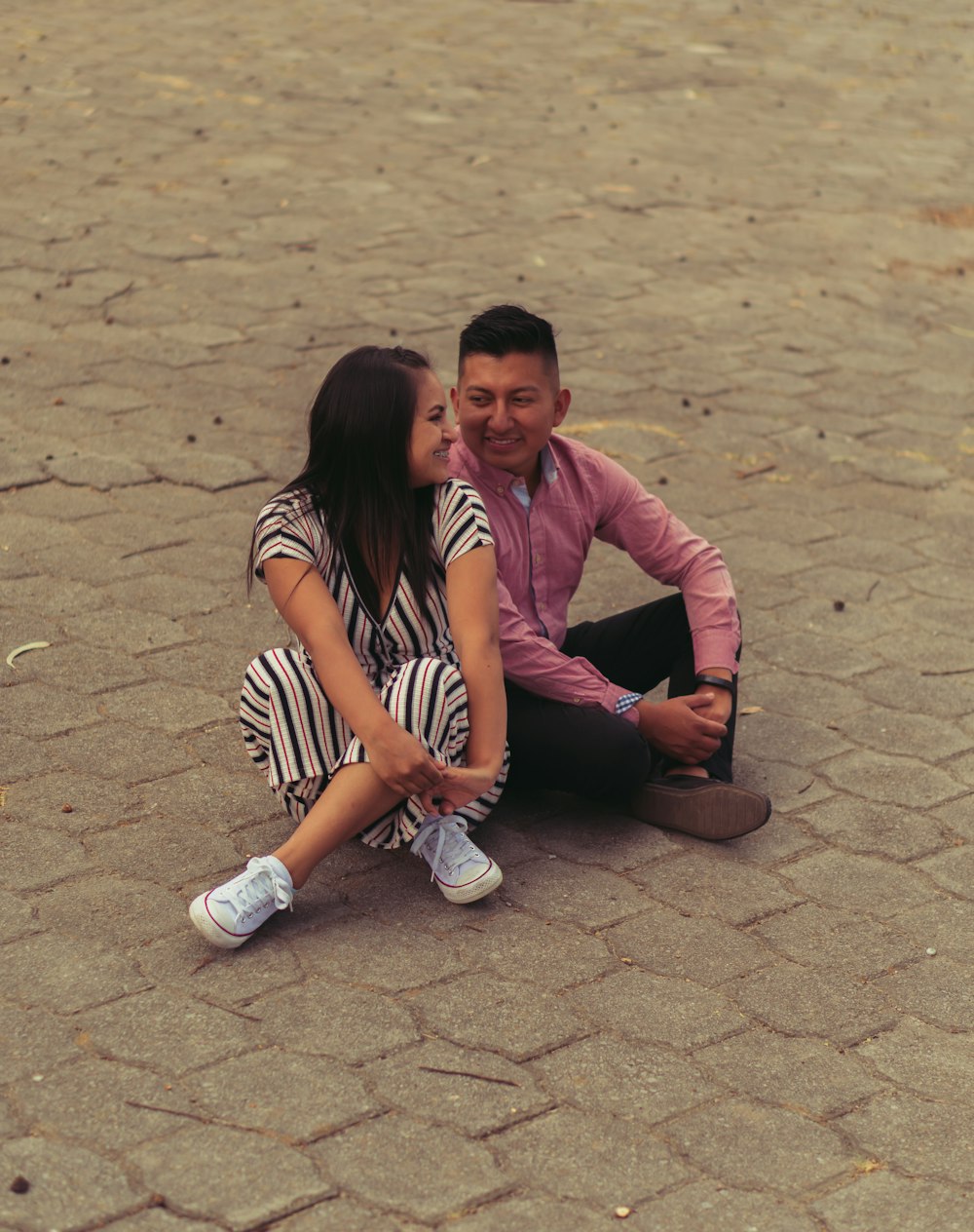 woman in pink long sleeve shirt sitting on brown concrete floor during daytime