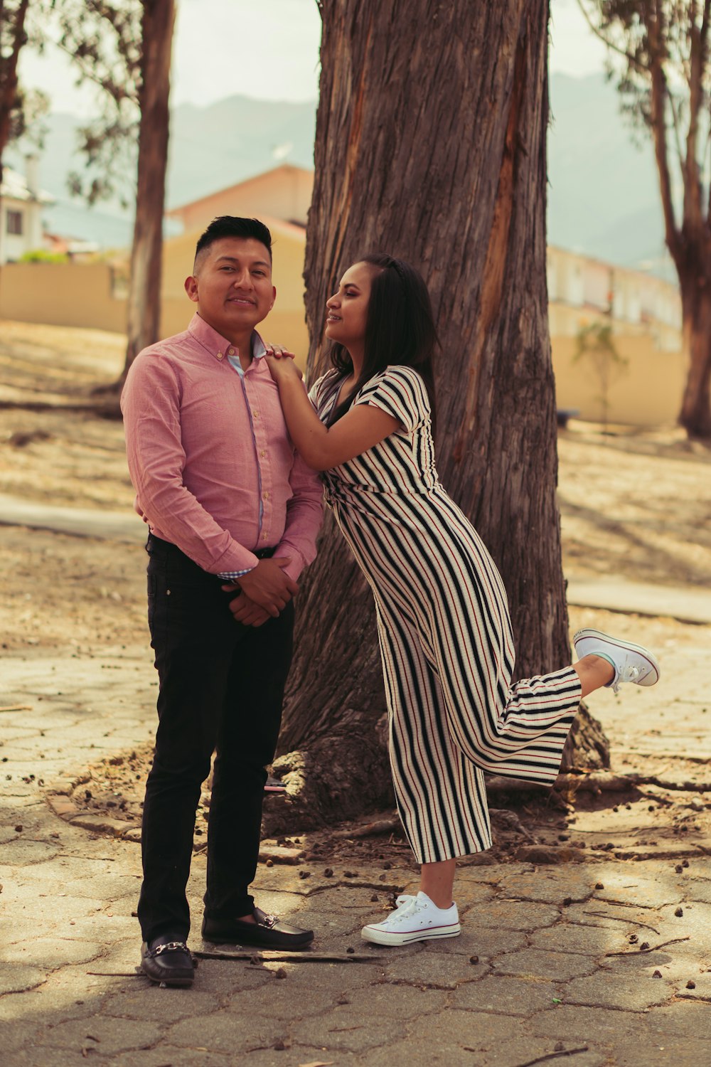 man in pink dress shirt and black pants standing beside woman in black and white stripe