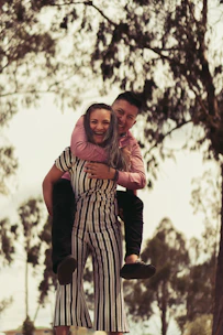 A caring mentor and a young person sharing a joyful moment outdoors.
