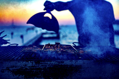 Twilight scene of the Smokecraft BBQ smoker glowing warmly as the event winds down.